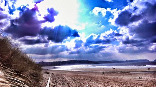 Scenic view of beach against cloudy sky