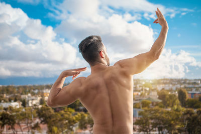 Rear view of shirtless man standing against sky