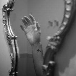 Close-up of hand with tattoo on mirror