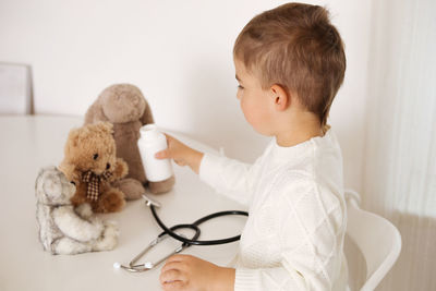 Cute little boy playing doctor at home and curing plush toy. sweet toddler child plays indoor. 