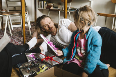 Father looking at daughter holding presents