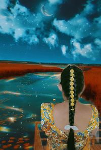 Rear view of woman standing by sea against sky