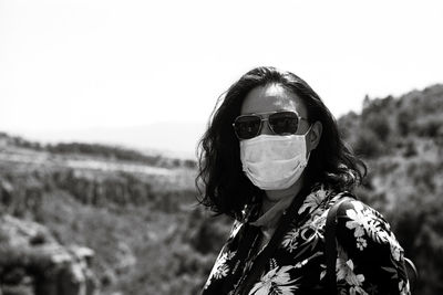 Portrait of woman wearing sunglasses and mask on field against sky