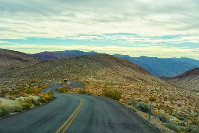 Road leading towards mountains against sky