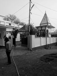 Rear view of woman standing on street against sky