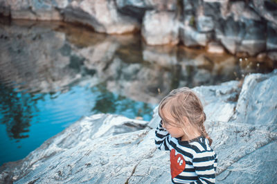 Rear view of boy on rock at shore