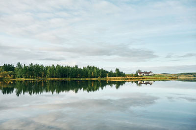 Beautiful landscape of green copse and house on lake shore