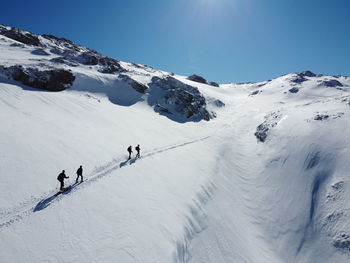 People skiing on snowcapped mountain against sky