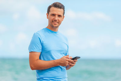 Portrait of young man standing against sea