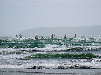 People windsurfing on sea against sky