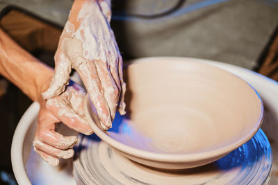 Cropped hands of potter making pot in pottery workshop