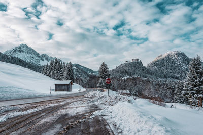 Snow covered road by trees against sky