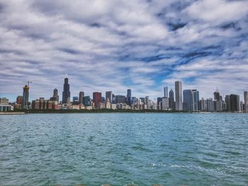 Sea by buildings in city against sky