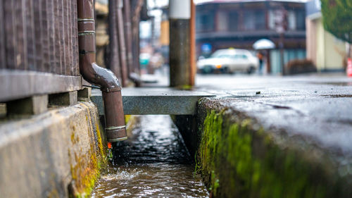 Water flowing from pipe on street by canal