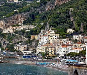 Buildings at sea shore against mountains