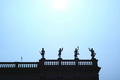 Low angle view of birds perched against clear sky