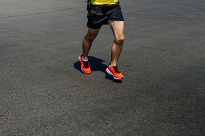Legs runner man in orange shoes running on dark road