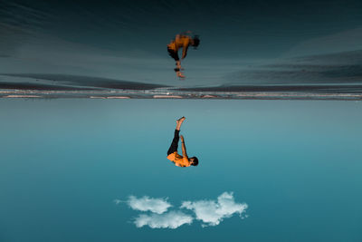 Low angle view of man jumping at sea against sky