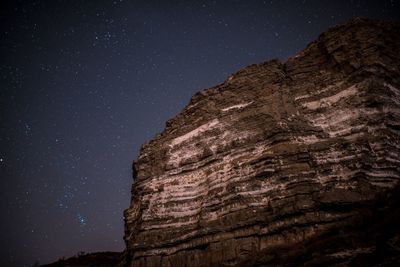 Low angle view of rock formation against sky at night