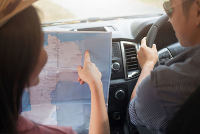 Close-up of girlfriend pointing on map with boyfriend driving car