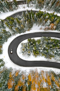 Aerial view of car on winding road in winter forest