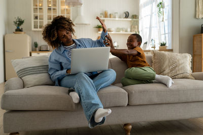 Young woman using laptop while sitting on sofa at home