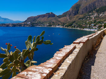 Scenic view of sea and mountains against clear blue sky