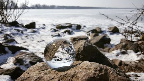 Close-up of crystal ball on rock by sea against sky