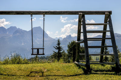 Chain swing hanging on wood against sky