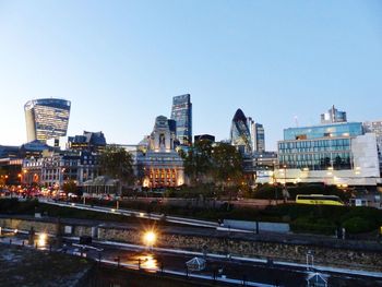 Illuminated buildings in city against clear sky