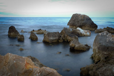 Rocks in sea against sky