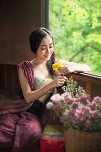 Beautiful woman holding red flowering plant