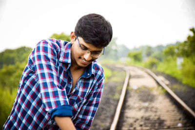 Young man standing by railroad track