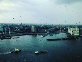 City against sky seen through wet window