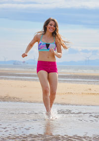 Full length of smiling young woman walking at beach
