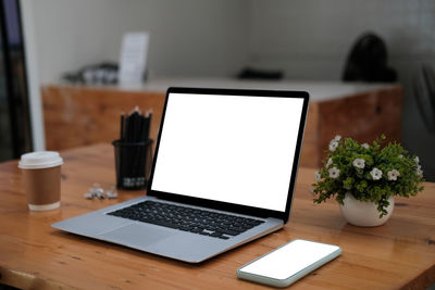 Close-up of mobile and laptop on table