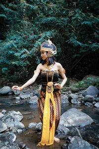 Full length of young woman standing on rock