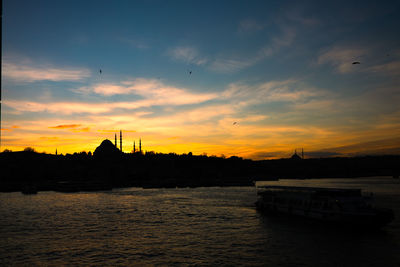 Silhouette boats in sea against orange sky