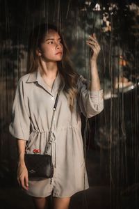 Portrait of young woman standing against black background