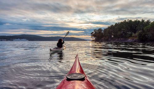 Rear view of man on boat against sky during sunset