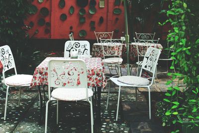 Empty chairs and table by plants at cafe