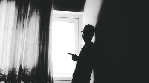 Silhouette man using mobile phone at home