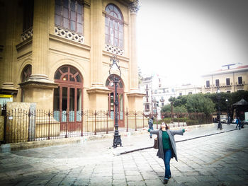 Rear view of people walking on street amidst buildings