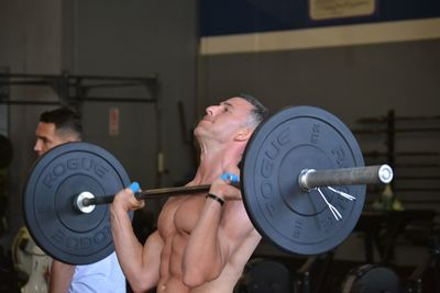 Mature man holding barbell at gym