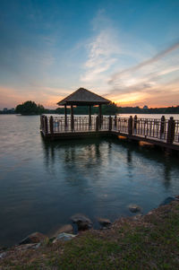 Jetty in lake against sky during sunset