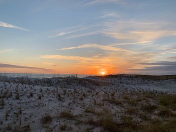 Scenic view of snow covered field against sky during sunset