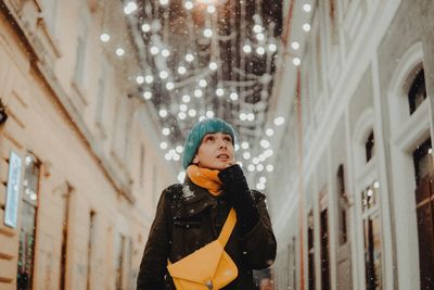 Young woman looking away while standing in illuminated room