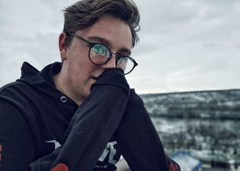 Portrait of young man with eyeglasses against sky