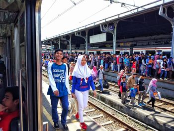 People standing on railroad track against sky