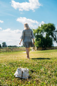 Rear view of woman standing on field against sky